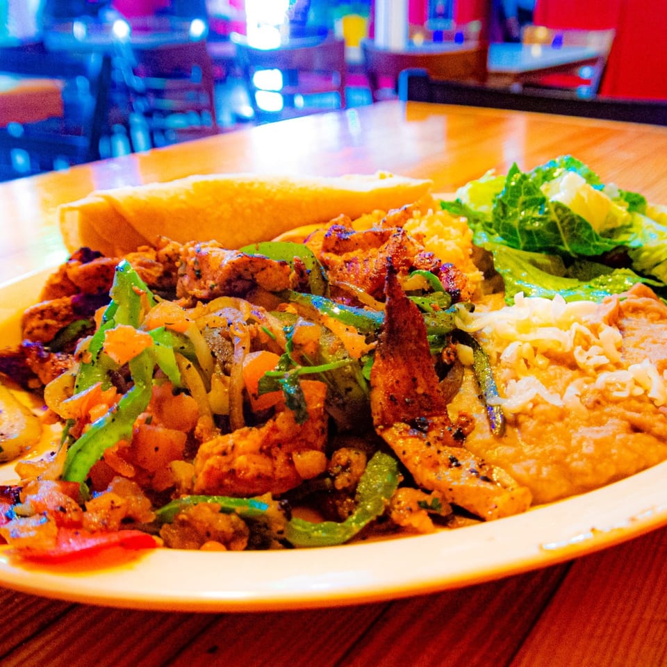 Los Cantaros Taqueria's fajitas with chicken, peppers, onions, rice, beans, and a tortilla.